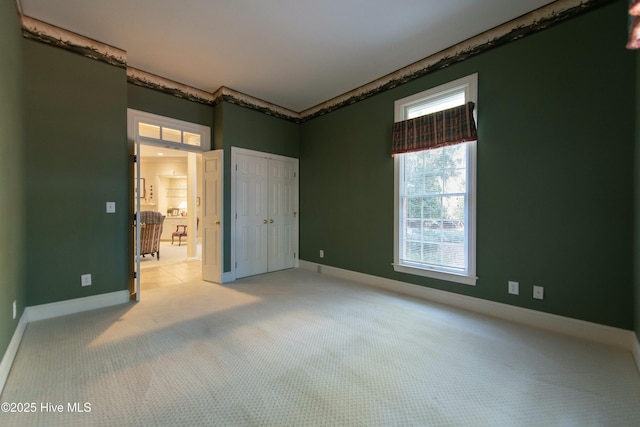 unfurnished bedroom with light colored carpet and a closet