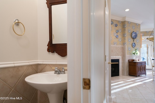 bathroom with ornamental molding, sink, tile walls, a fireplace, and tile patterned flooring