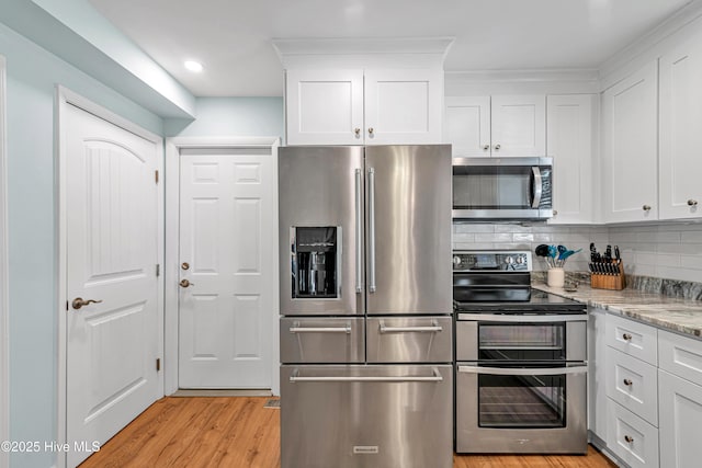 kitchen featuring white cabinetry, stainless steel appliances, tasteful backsplash, light stone counters, and light hardwood / wood-style flooring