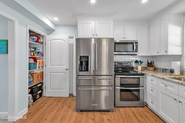 kitchen featuring stainless steel appliances, tasteful backsplash, light wood-type flooring, white cabinets, and light stone counters