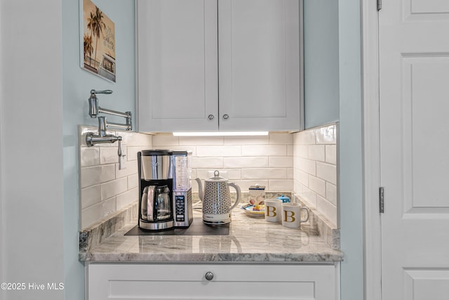 kitchen with decorative backsplash, light stone counters, and white cabinetry