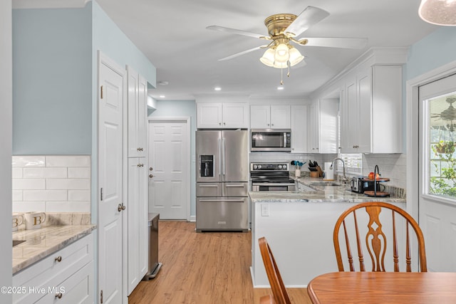 kitchen with ceiling fan, decorative backsplash, sink, white cabinetry, and stainless steel appliances