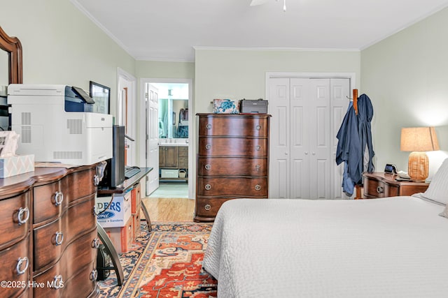 bedroom with a closet, ensuite bathroom, crown molding, and wood-type flooring