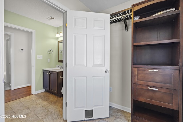 walk in closet with light tile patterned floors and sink