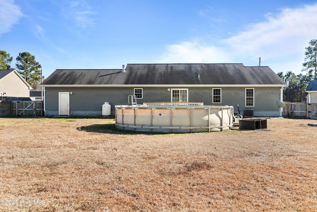 rear view of house featuring central AC, a yard, and a fenced in pool