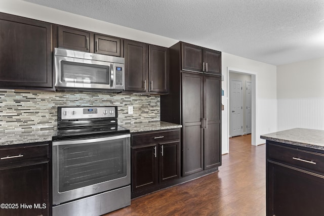 kitchen featuring dark wood-type flooring, stainless steel appliances, dark brown cabinets, and light stone counters