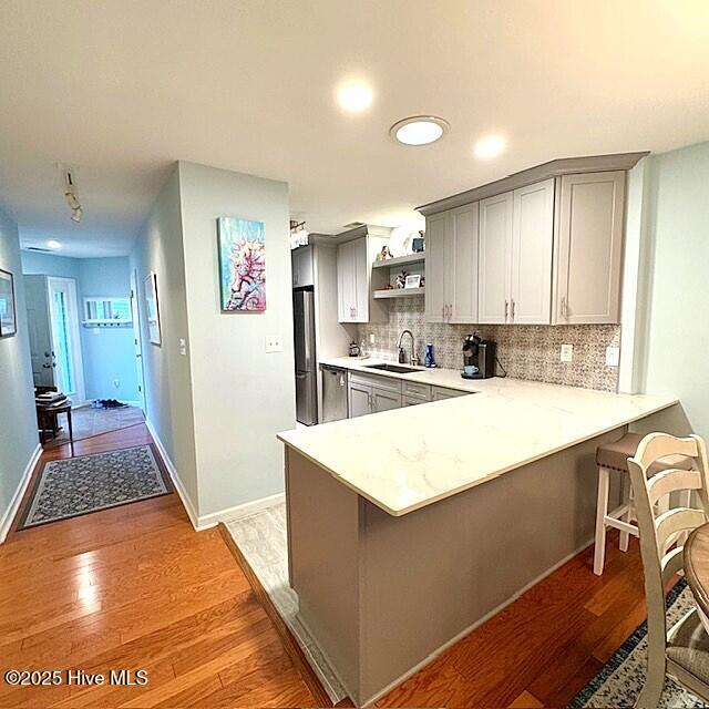 kitchen featuring kitchen peninsula, sink, gray cabinets, and light hardwood / wood-style floors