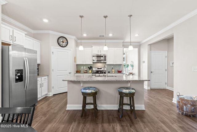 kitchen featuring white cabinets, hanging light fixtures, an island with sink, and appliances with stainless steel finishes