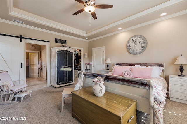 carpeted bedroom featuring crown molding, a tray ceiling, a barn door, and a spacious closet