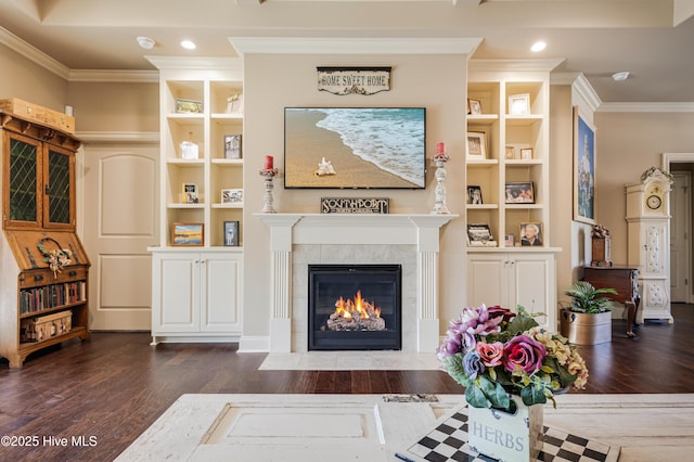 living room featuring dark wood-type flooring, crown molding, and a tiled fireplace