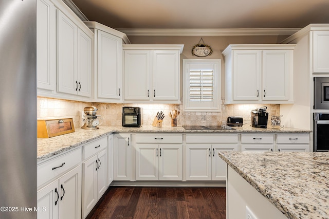 kitchen with light stone counters, backsplash, crown molding, and white cabinets