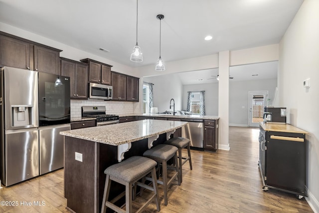 kitchen with ceiling fan, kitchen peninsula, a breakfast bar area, pendant lighting, and appliances with stainless steel finishes