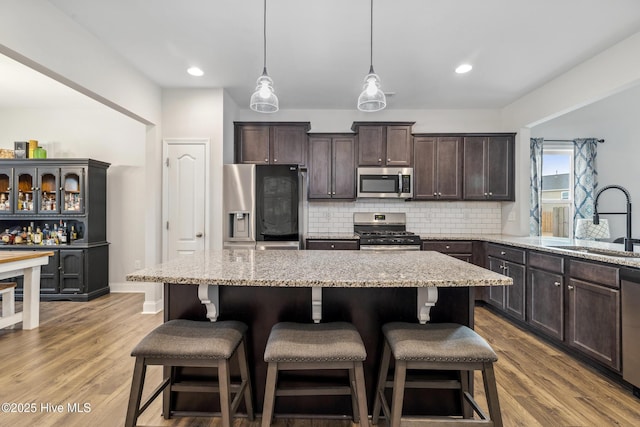 kitchen featuring a kitchen breakfast bar, stainless steel appliances, hanging light fixtures, a center island, and sink