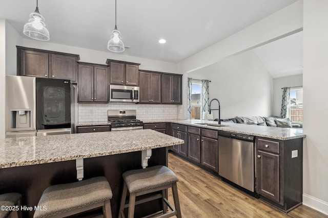 kitchen with appliances with stainless steel finishes, tasteful backsplash, decorative light fixtures, and sink