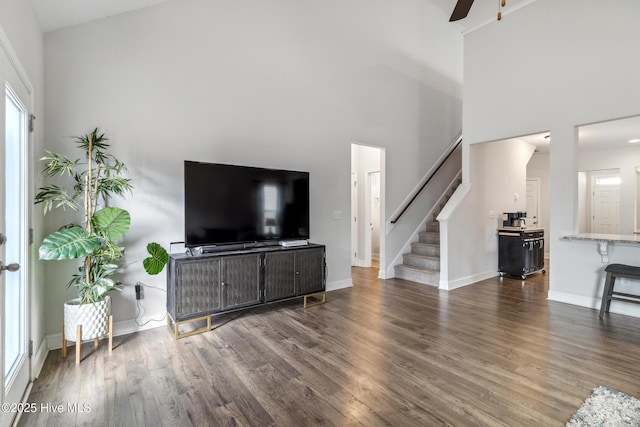 living room with a towering ceiling, ceiling fan, and dark hardwood / wood-style flooring