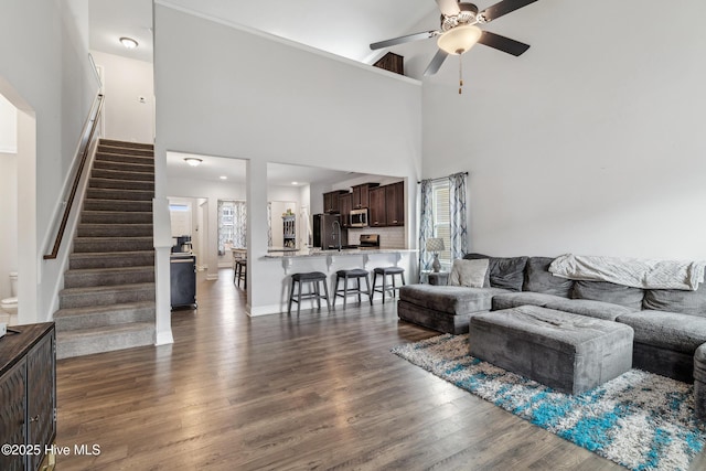 living room featuring ceiling fan, dark hardwood / wood-style flooring, and a high ceiling