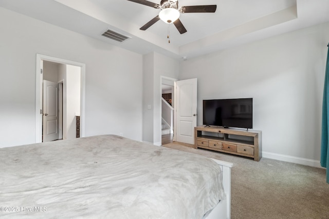 bedroom with a raised ceiling, ceiling fan, and light carpet