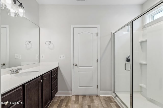 bathroom with hardwood / wood-style floors, vanity, and a shower with shower door