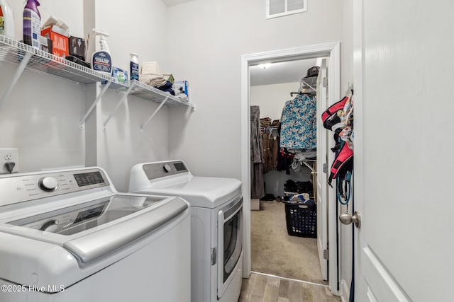 laundry room with washer and clothes dryer and light hardwood / wood-style flooring