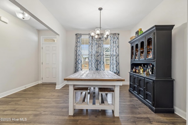 dining area featuring indoor bar, a notable chandelier, and dark hardwood / wood-style floors