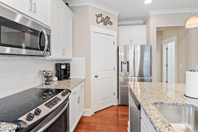 kitchen featuring stainless steel appliances, decorative backsplash, white cabinetry, and hanging light fixtures