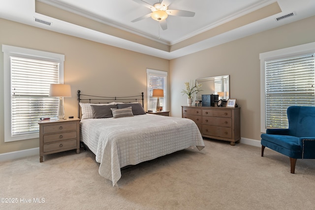 carpeted bedroom with ceiling fan, a tray ceiling, and ornamental molding