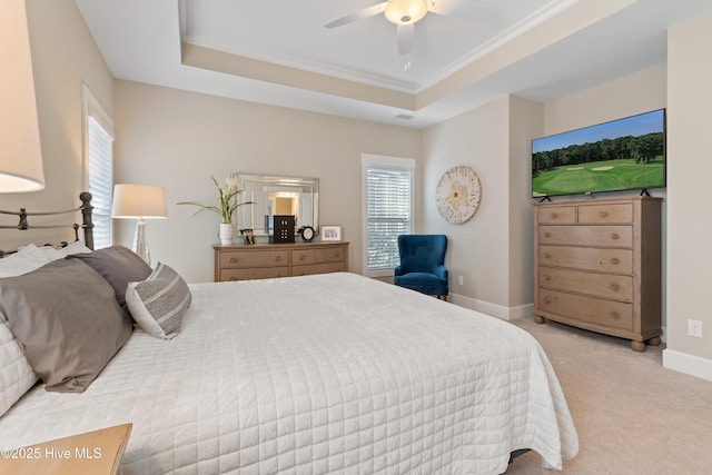 bedroom featuring ornamental molding, light colored carpet, ceiling fan, and a tray ceiling