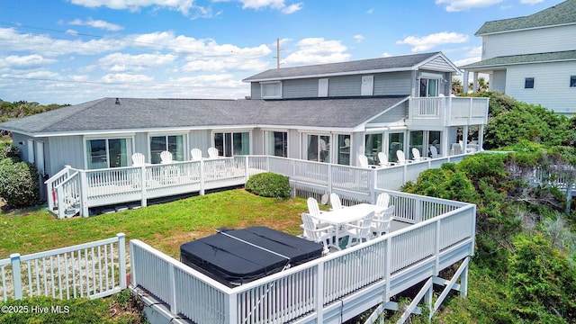 rear view of property featuring a yard, a hot tub, and a deck