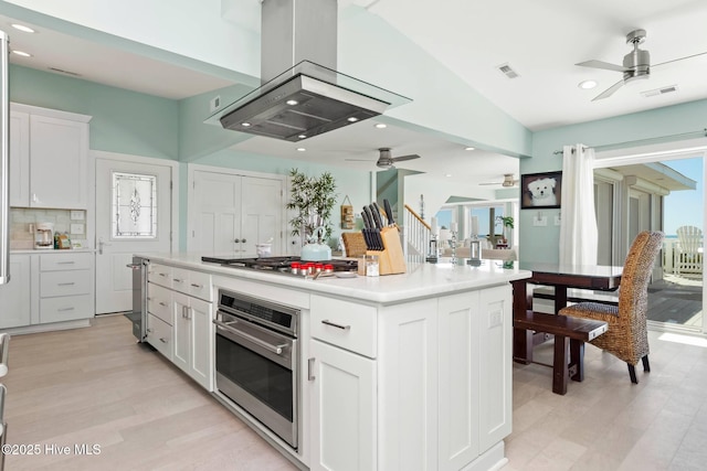 kitchen featuring island range hood, a kitchen island, white cabinetry, and appliances with stainless steel finishes