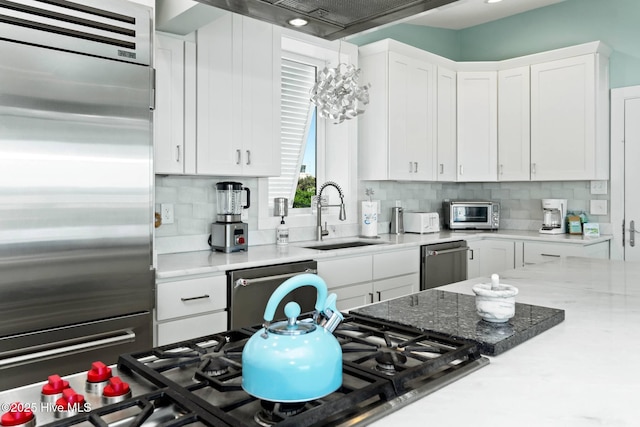 kitchen with tasteful backsplash, white cabinetry, sink, and stainless steel appliances