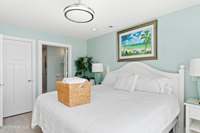 bedroom with ensuite bathroom and light hardwood / wood-style flooring