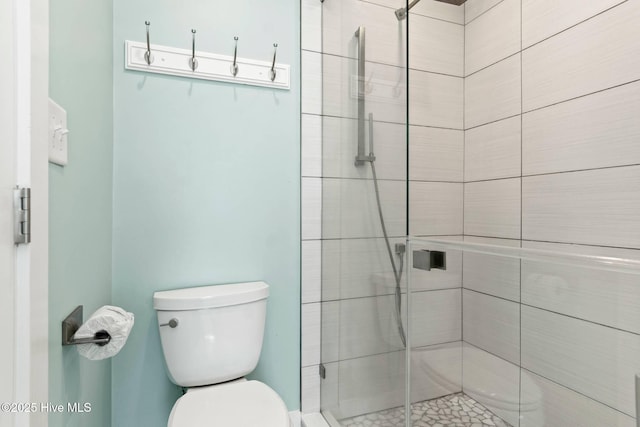 bathroom with toilet and a shower with door