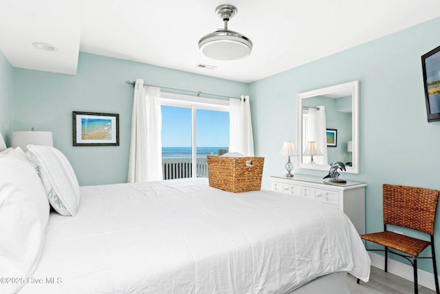 bedroom featuring a water view, light wood-type flooring, and access to outside