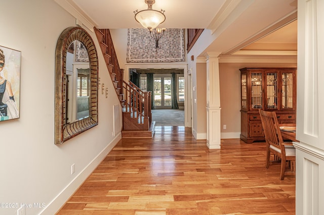 foyer entrance with french doors, a notable chandelier, ornamental molding, and light hardwood / wood-style floors