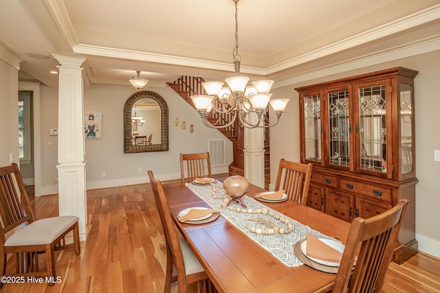 dining space featuring ornate columns, crown molding, light hardwood / wood-style flooring, and an inviting chandelier