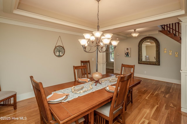 dining room featuring wood-type flooring, a tray ceiling, ornamental molding, and an inviting chandelier