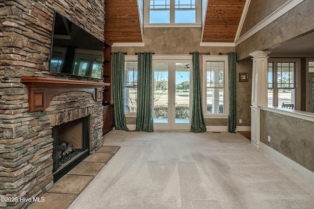 unfurnished living room featuring light carpet, wood ceiling, a stone fireplace, french doors, and high vaulted ceiling