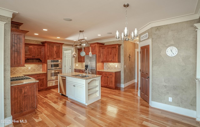 kitchen with decorative light fixtures, sink, a kitchen island with sink, and stainless steel appliances