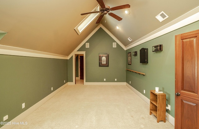 interior space with ceiling fan, ornamental molding, and lofted ceiling with skylight