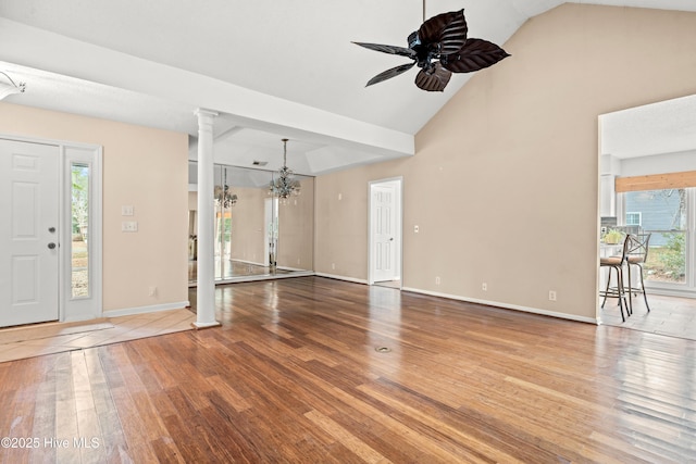 entrance foyer featuring vaulted ceiling, plenty of natural light, ceiling fan with notable chandelier, and hardwood / wood-style flooring