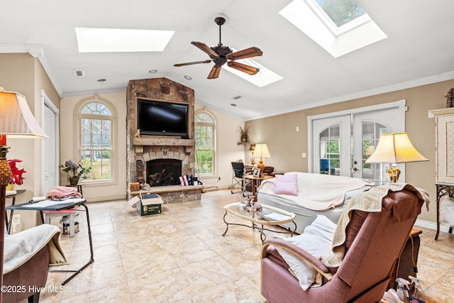 living room featuring ceiling fan, vaulted ceiling, a fireplace, crown molding, and french doors