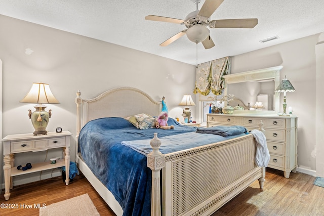 bedroom with ceiling fan, a textured ceiling, and light hardwood / wood-style floors