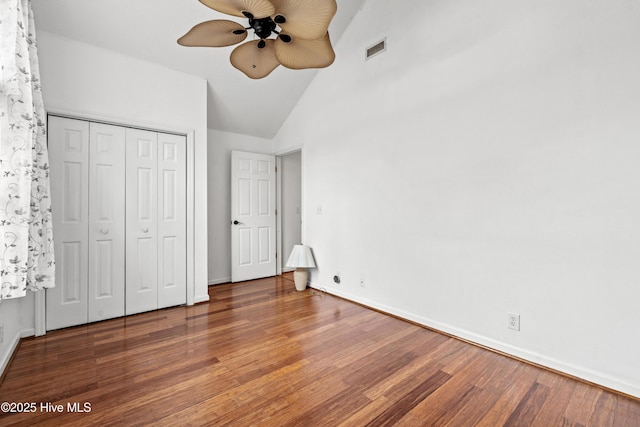 unfurnished bedroom featuring ceiling fan, a closet, dark hardwood / wood-style flooring, and lofted ceiling