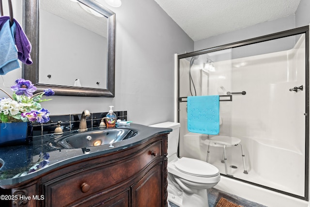 bathroom with a shower with shower door, vanity, toilet, and a textured ceiling