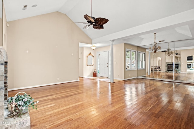 unfurnished living room with ceiling fan with notable chandelier, light hardwood / wood-style flooring, ornate columns, and vaulted ceiling