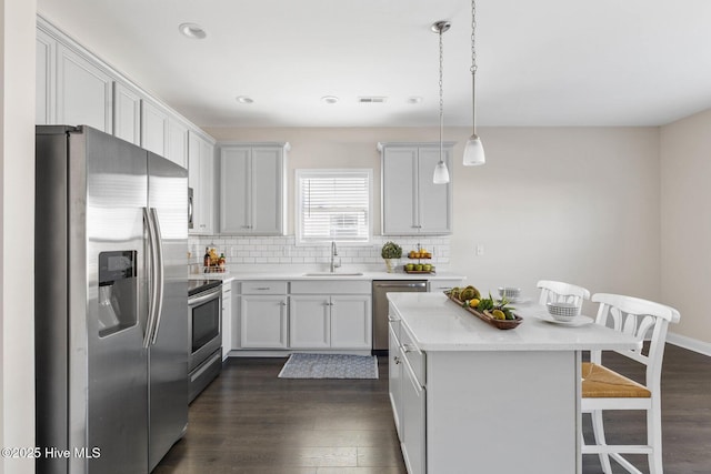 kitchen featuring a breakfast bar, sink, hanging light fixtures, a kitchen island, and stainless steel appliances