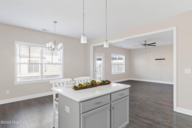 kitchen with dark hardwood / wood-style flooring, a kitchen island, a kitchen breakfast bar, and decorative light fixtures