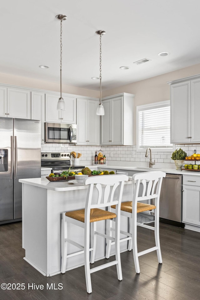 kitchen with stainless steel appliances, dark hardwood / wood-style floors, a center island, and hanging light fixtures