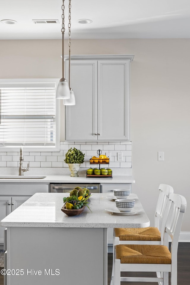 kitchen with hanging light fixtures, decorative backsplash, sink, and dishwasher