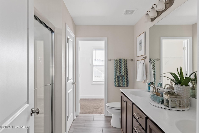 bathroom featuring vanity, toilet, and a shower with shower door